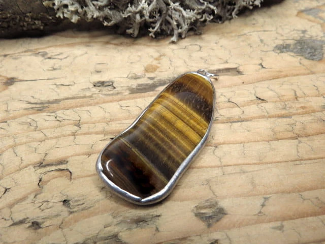 Wisior z tygrysiego oka – kamienia odwagi, ochrony i bogactwa. Ręcznie oprawiony w miedź i cynę. Naturalna biżuteria przyciągająca dobrobyt.