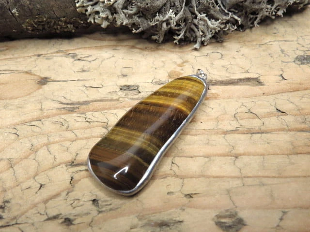 Wisior z tygrysiego oka – kamienia odwagi, ochrony i bogactwa. Ręcznie oprawiony w miedź i cynę. Naturalna biżuteria przyciągająca dobrobyt.