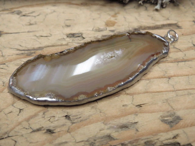 Wisior z polerowanego plastra agatu – kamienia ochrony ogniska domowego. Ręcznie oprawiony w miedź i cynę. Amulet spokoju, harmonii i stabilności.