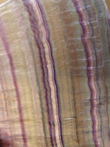 Wyjątkowy okaz tęczowego fluorytu w formie płytki, starannie wypolerowanej z obu stron. Kamień zachwyca naturalnym układem barw – odcienie fioletu, zieleni i błękitu układają się w subtelne pasy, tworząc niepowtarzalną kompozycję.