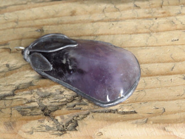 Ręcznie wykonany wisior z naturalnego, polerowanego ametystu o fioletowej barwie i delikatnych przejściach kolorów.