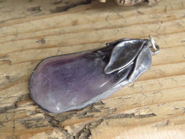 Ręcznie wykonany wisior z naturalnego, polerowanego ametystu o fioletowej barwie i delikatnych przejściach kolorów.