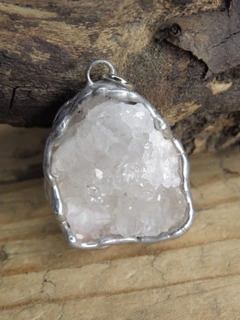 Ręcznie wykonany wisior z naturalną szczotką krystaliczną kryształu górskiego. Liczne, błyszczące kryształki tworzą efektowną, trójwymiarową strukturę, która pięknie odbija światło i podkreśla naturalne piękno minerału.