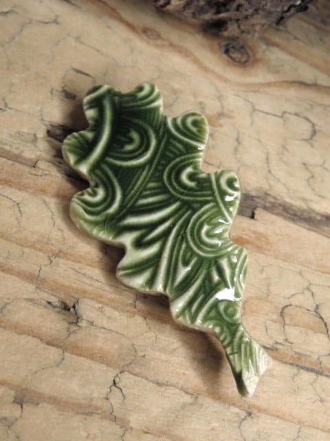 Ręcznie wykonana ceramiczna broszka w kształcie liścia z Pracowni Ceramiki Kuźni Alchemicznej. Pokryta szkliwem w odcieniach zieleni.